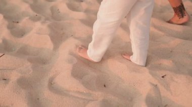 Kumda yürürken ayaklarınızı kapatın. Anne ve oğlu güneşli bir sahilde yürüyüş yapıyorlar. İyi tatiller..