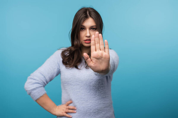 Confident woman extending hand assertively, expressing rejection or denial. Ideal for themes of boundaries, refusal, communication, and assertiveness in professional and personal contexts on vibrant