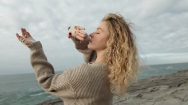 Sanatçı genç bir kadın, bulutlu bir günde sakin bir okyanus zeminine karşı dans ederek özgürlüğünü ifade eder..