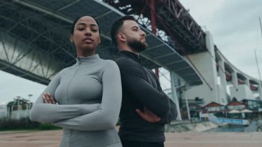 Düşük açılı bir bakış açısı, takım çalışmasının özünü yakalar, formda bir kadın ve antrenörü sırt sırta verip, güç ve kararlılık saçar..