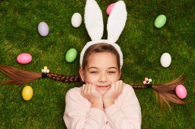 Yeşil çimenlerde uzanan beyaz kulaklı güzel bir kız manzarası.