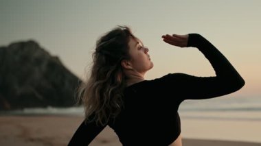 Gün batımında bir kadın kumsalda zarif bir şekilde dans eder. Huzur ve güzelliğin özünü yakalar. Huzurlu sahne, doğa ve özgürlükle bir bağ hissi uyandırıyor..