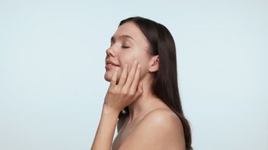 Temiz yüzlü, açık mavi arka planda tenine dokunan doğal bir güzelliğin portresi..