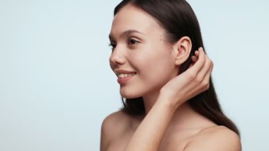 Genç bir kadının saçlarını düzeltmesi ve bir güzellik konseptine hazırlanması. Sade bir arka plan..