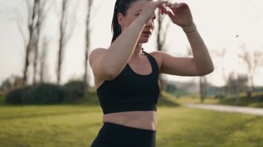 Açık hava boks antrenmanına katılan odaklanmış sporcu bir kadın, doğal ortamında bacak tekmesi pratiği yapıyor..