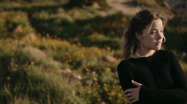 Bir tarlada durup güneşin tadını çıkaran genç bir kadın. Geniş kopya alanına sahip huzurlu ve huzurlu doğal ortam.