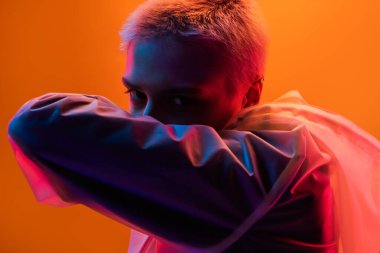 Fütüristik tonları olan parlak neon ışıklı bir kadının yaratıcı portresi. Turuncu ve mor renkler büyüleyici bir modern estetik yaratıyor..