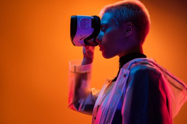 Bir insan, canlı neon ışıklara karşı duran sanal gerçekliği bir VR kulaklıkla keşfeder. Sahne, yenilik ve geleceğin teknolojisini fütüristik ve şık kavramların karışımıyla aktarıyor..