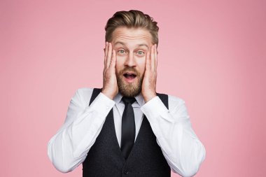 İş kıyafeti giymiş bir adam, şaşkınlığını dile getiriyor, canlı pembe bir arka plana karşı poz veriyor, sürpriz ve profesyonelliği simgeliyor..