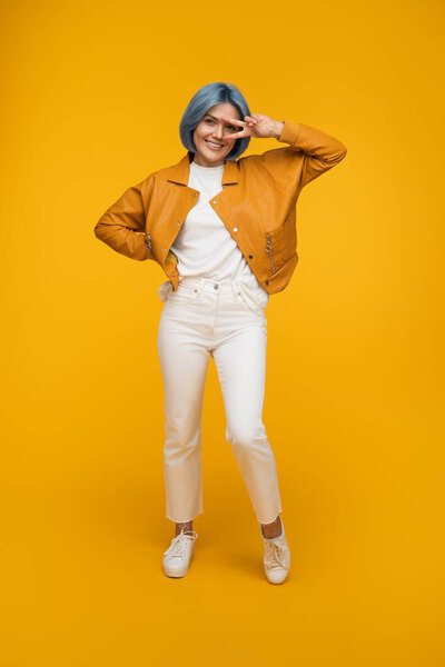 A cheerful individual dressed in vibrant clothing poses energetically against a vivid yellow background, expressing joy and positivity.