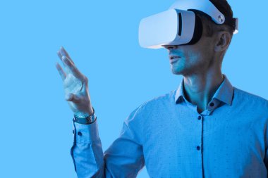 VR kulaklık takan ve sanal arayüzle etkileşime geçen bir adam gelecekteki teknolojiyi ve deneyimleri simgeliyor..