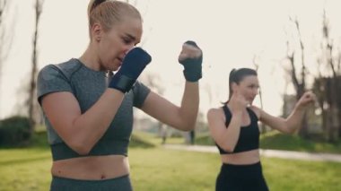 İki atletik kadın, enerjik bir açık hava boks antrenmanında güç ve ortaklık gösteriyorlar..
