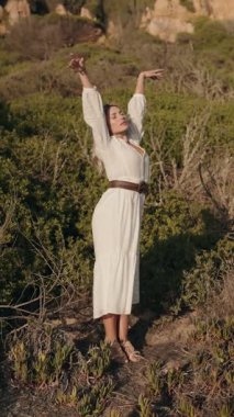 Beyaz elbiseli sarışın bir kadın doğanın huzurunu kucaklıyor. Huzurlu bir manzaranın ortasında özgürlük ve barış jesti olarak kollarını kaldırıyor..