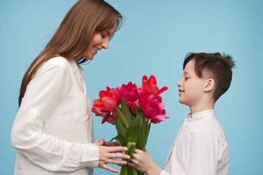 Neşeli çocuk üzerinde 8 Mart tatil tebrik Anne için güzel Lale vererek yan görünüm