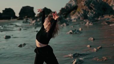 Resimli bir plajda zarif bir şekilde gösteri yapan büyüleyici bir dansçı görüntüsü, doğal güzelliğin ortasında özgürlük ve yaratıcılığı somutlaştırıyor..