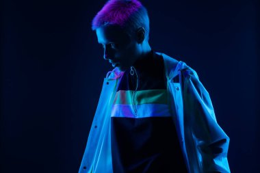 Modern tarzı olan kendine güvenen bir birey, fütüristik ve enerjik bir havayı vurgulayan parlak neon ışıklarıyla aydınlanır..