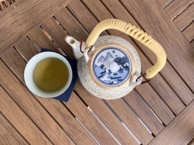 Çay saati, çaydanlıklı ahşap tepsi, masada doğal papatya çayı ve çiçekler, cam bardaklar ve cam çaydanlık. Termal cam çay fincanları. Parlak sabah çayı..