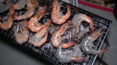 Nehir karideslerinin kömür ocağında ızgara yaptığı videoyu kapat. Tayland deniz ürünleri sokak yemekleri dumanlı aromalı, geleneksel mangal kömürü ızgarası, taze karides ve lezzetli yerel mutfak konsepti..