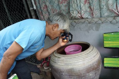 Sivrisinek larvalarını araştıran gönüllü vatandaşlar, sivrisinek üreme alanlarını yok ederek su kabını alt üst ediyorlar. Dang hummasını önleme, 16 Ocak 2024, Buriram Tayland.