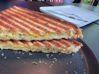 Taze pişmiş jambonlu ve peynirli sandviçte erimiş peynir, tuzlu jambon ve altın ekmek kahvaltıda, öğle yemeğinde ya da aperatifte sıcak, lezzetli ve tatmin edici bir yemek sunulur..