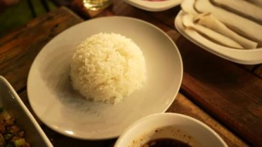 Tabakta servis edilen sıcak beyaz pirinç videosunu kapat. Basit ve taze Asya yemekleri, günlük yemeğin, konforlu gıdanın ve sağlıklı beslenmenin sembolü. Yemek, yaşam tarzı ve mutfak kavramları için mükemmel..