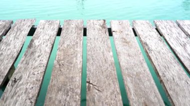 Su üzerindeki ahşap palet köprüsünün yemyeşil pirinç tarlasında 4K videosu. Kırsal yaşam tarzı, huzurlu kırsal atmosfer, doğal manzara ve Tayland tarım arazilerindeki basit yaşam. Seyahat, doğa ve kültürel temalar için mükemmel..