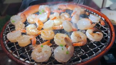 Yakın plan Karides Pişirme ve Ağır Duman Bir Sıcak Barbekü Sobası, Bir Geleneksel Restoranda Bir Duman Bulutunda Karidesleri Izgara.