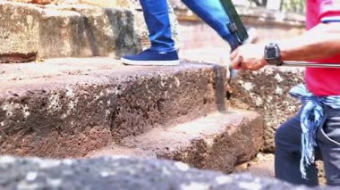 Bir turistin antik taştan bir kaleyi veya tarihi bir yeri gezerken ve keşfederken çekilmiş videoları doğal güneş ışığı altında ayakkabılarını parlaklaştırıyor. Seyahat, miras turizmi, kültür ve tarih için mükemmel..