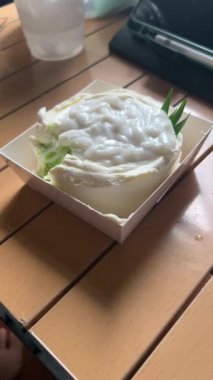 Hindistan cevizli kek, ahşap masaya yerleştirilmiş lezzetli hindistan cevizli kek videosunu kapat. Taze pişmiş kremalı tatlı, fırın, tatlı, pasta, ev yapımı ikramlar ve yiyecek için mükemmel bir tema..