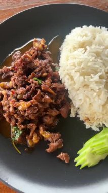 4K yakın çekim videosu, Tayland fesleğenli biftek kızartması aromatik otlar, cızırdayan etler ve ışıl ışıl baharatlı sos. Otantik Asya sokak yemekleri, aromalı Tayland yemekleri ve ev yapımı lezzetli yemekler.