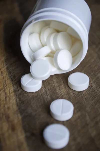 White pills. Medical tablets in white plastic packaging. White pills poured out of the box onto a wooden table.