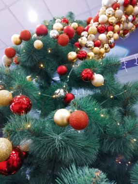 Kırmızı ve sarı Noel ağacı oyuncakları asılır. Ağaçtaki Noel toplarının kompozisyonu. Dikey fotoğraf - Noel ağacı süslemesi ve yeni yıl için.