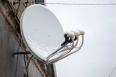 Evin üzerinde bir uydu anteni asılı. Evin duvarında beyaz bir uydu anteni var. Özel sektör için uydu anteni.