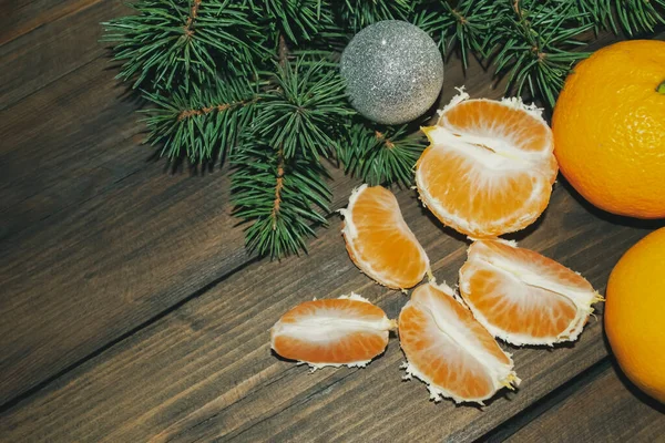 在绿色云杉的背景上 有一片片橘子 在一棵装饰过的圣诞树的背景上装饰着唐吉林 剥皮的橘子和有球的圣诞树 — 图库照片