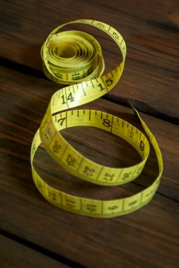 Tahta bir masaya dikmek için sarı metre. Fotoğraf yanlış açıdan çekilmişti. Masanın üzerinde ölçmek için bir metre var..