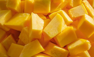 Arka planda turuncu balkabağı parçaları. Balkabağı küpleri arka planda. Sarı balkabağı parça parça.