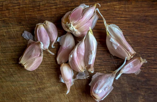 Garlic on the table. Parts of a head of garlic on a wooden table. Garlic is broken on a wooden background.