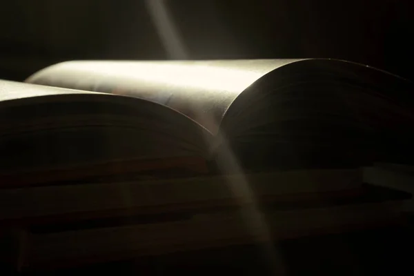Rays of light fall on the open book. Light from an open book. An open book under light. A book in direct sunlight.