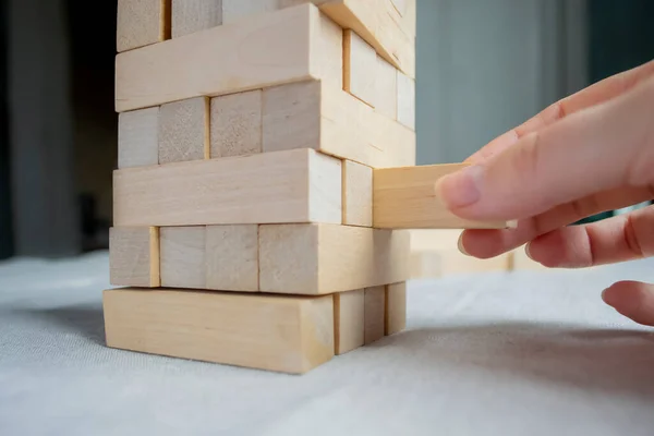 A hand pulls out an element from the wooden board game Tower. Game Tower board - the process of getting a block. wooden board game Tower.