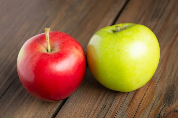 Red and green apple on a wooden table. Healthy fruits on the table. On a wooden board lies one red and one green apple.