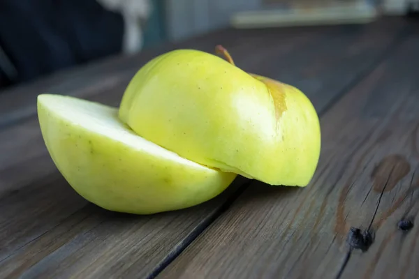 The cut apple is green. Two halves of an apple on a wooden table.