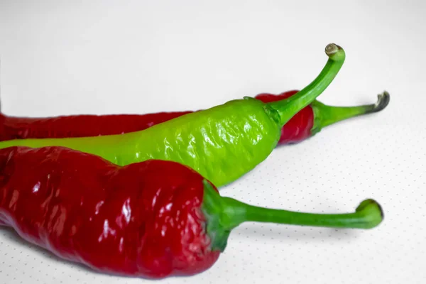 Hot pepper on a white background. On the white there are two red and one green pepper pods. Chili peppers on a white background. Three peppers. Green and red hot pepper.