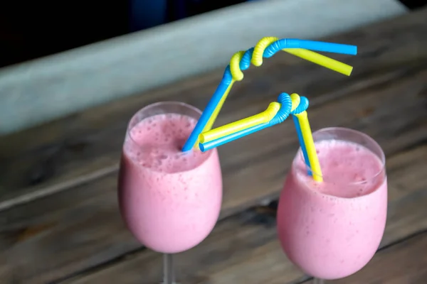 Two pink cocktails with yellow-blue straws. Cocktail straws are the colors of the flag of Ukraine. Yellow-blue straws in a cocktail on the table. Two cocktails.