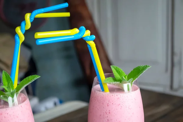 Two pink cocktails with yellow-blue straws. Cocktail straws are the colors of the flag of Ukraine. Yellow-blue straws in a cocktail on the table.