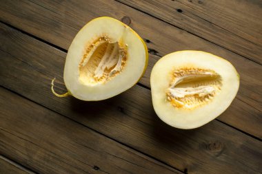 Two halves of a melon on a wooden table. Two parts of a melon. A young, sweet melon without seeds.