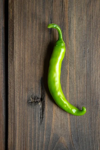 Green chili pepper pod on a wooden table. green chili pepper. hot pepper green. pepper on the table.