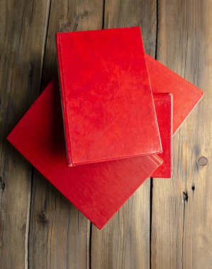 Lots of red books, view from above. On the wooden table are books with a red cover. Hardcover books, with a red cover on the table.