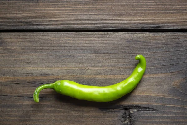 Green chili pepper pod on a wooden table. green pepper on the table. green chili pepper. hot pepper green.