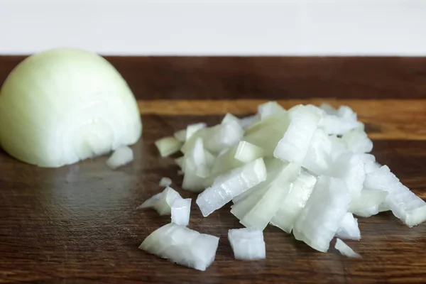Chopped onions on a wooden board. Chopped onions on the table. On a wooden board, half an onion and a second, chopped half.