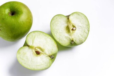 Beyaz arka planda yeşil bir elmanın iki yarısı. Beyazın üzerinde doğranmış yeşil bir elma var. Yeşil kesiği kapatıyorum. Sağlıklı meyve.
